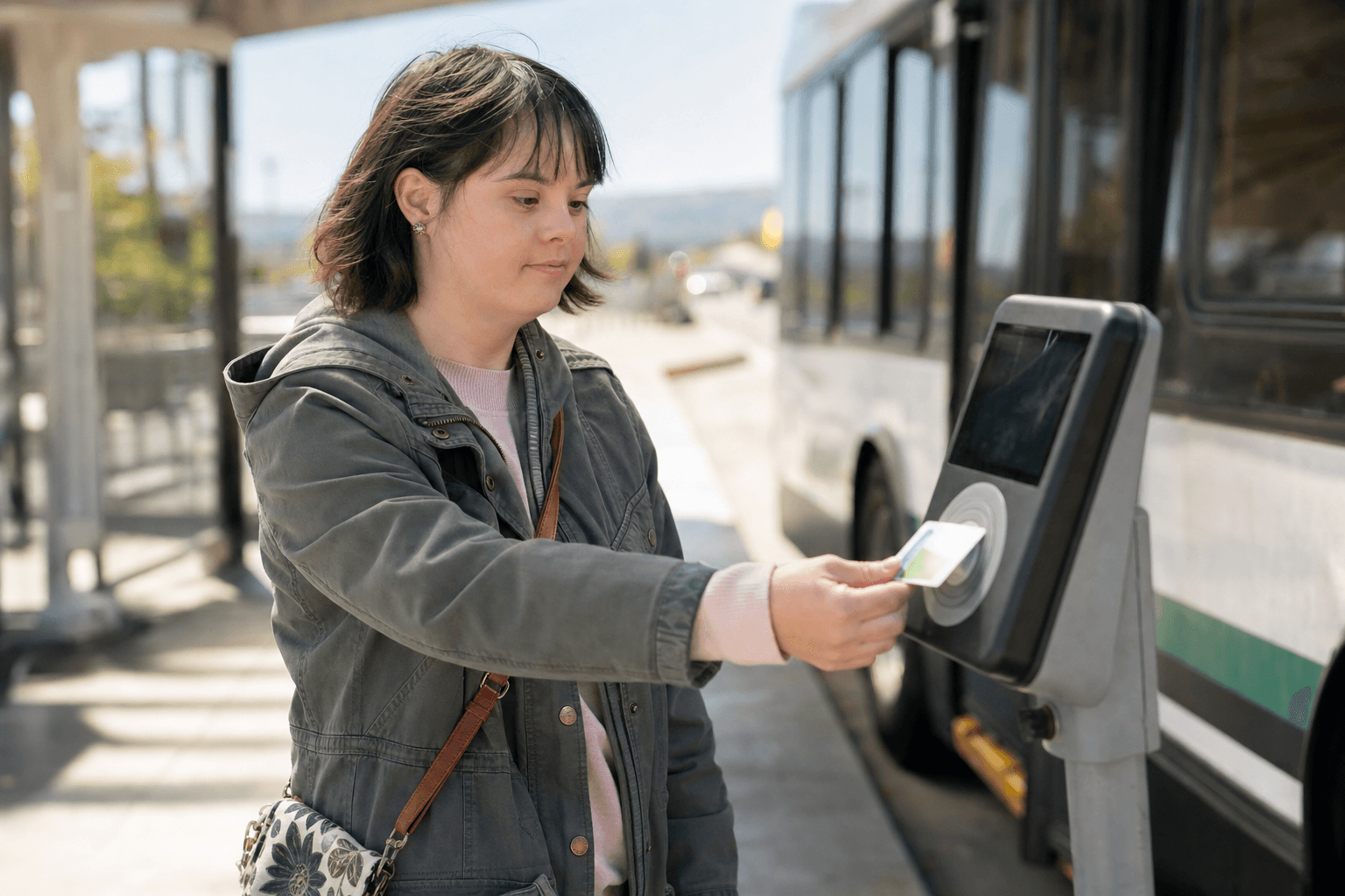 A young woman tapping a transit card on a fare reader at a bus stop in the Bay Area.